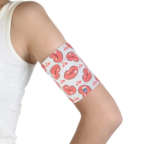 Protective armband with pink heart design securing glucose sensor on teenager's upper arm.