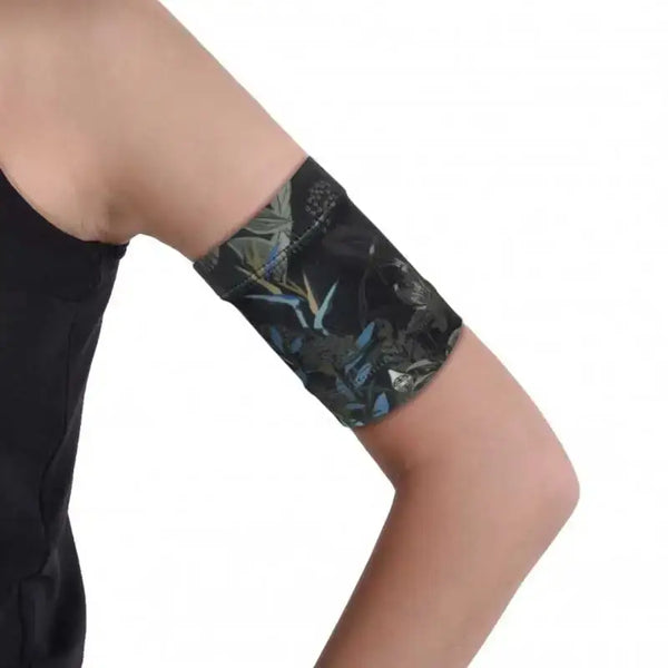 Stylish blood glucose sensor armband in dark printed fabric on arm.