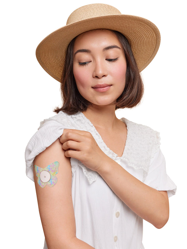 FreeStyle Libre 2 butterfly shape patch worn on a woman’s arm, with breathable adhesive fabric for sensor support