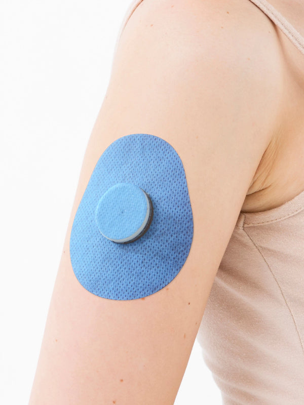 FreeStyle Libre 2 drop shape patch close-up on arm, showing breathable adhesive support around the sensor