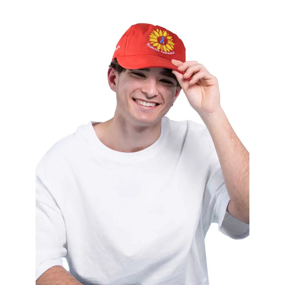 Red Kaio-Caps Diabetes Awareness Cap with sunflower emblem worn by smiling person.